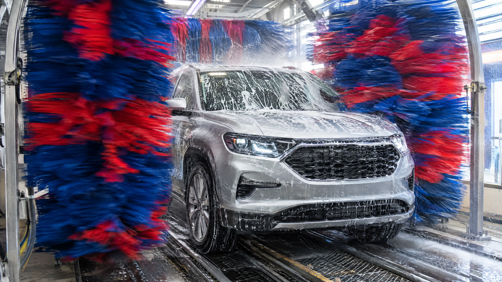 Wrap brushes closing around an SUV inside an express car wash tunnel.